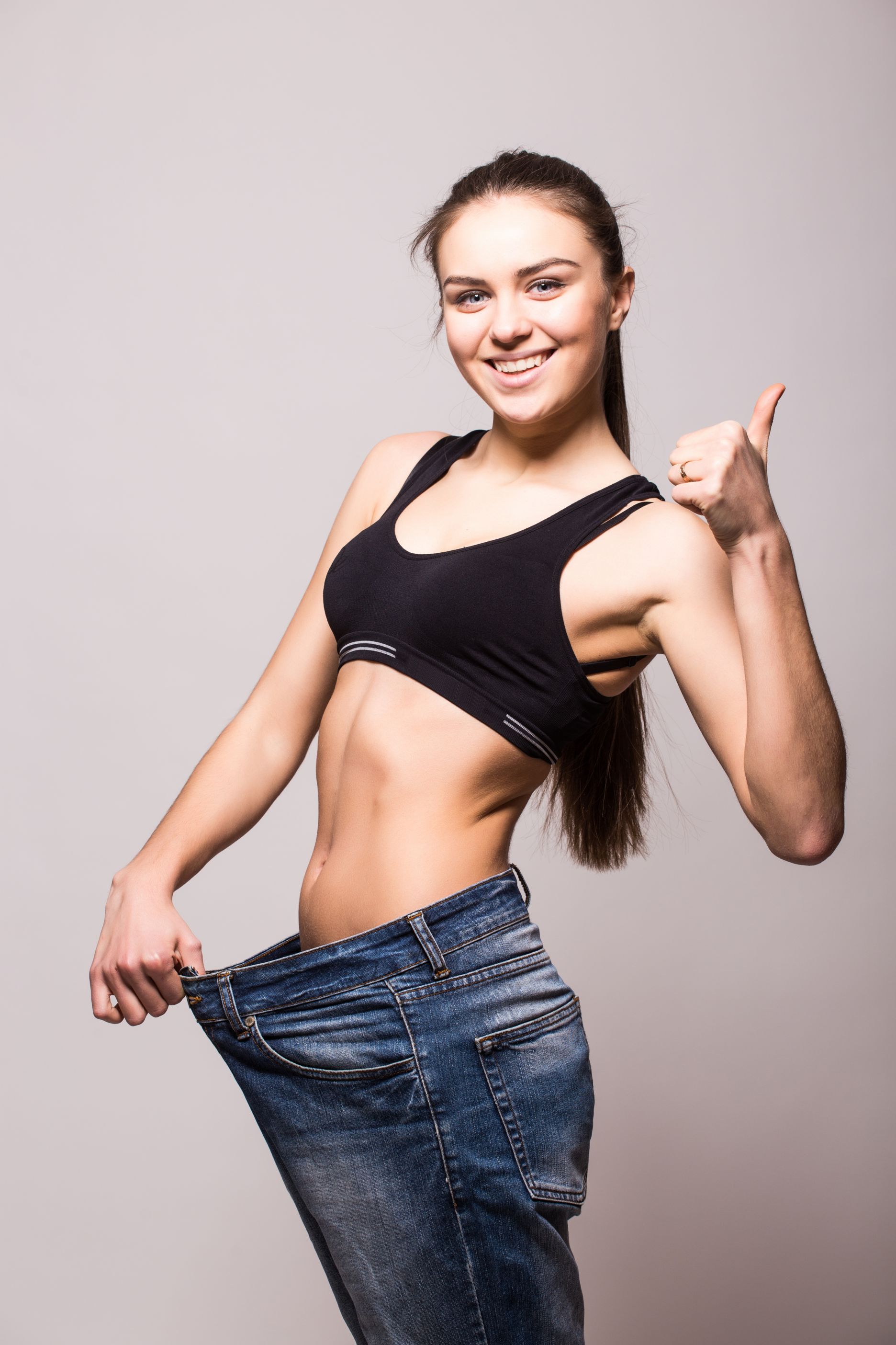 young-woman-shows-her-weight-loss-by-wearing-old-jeans.jpg